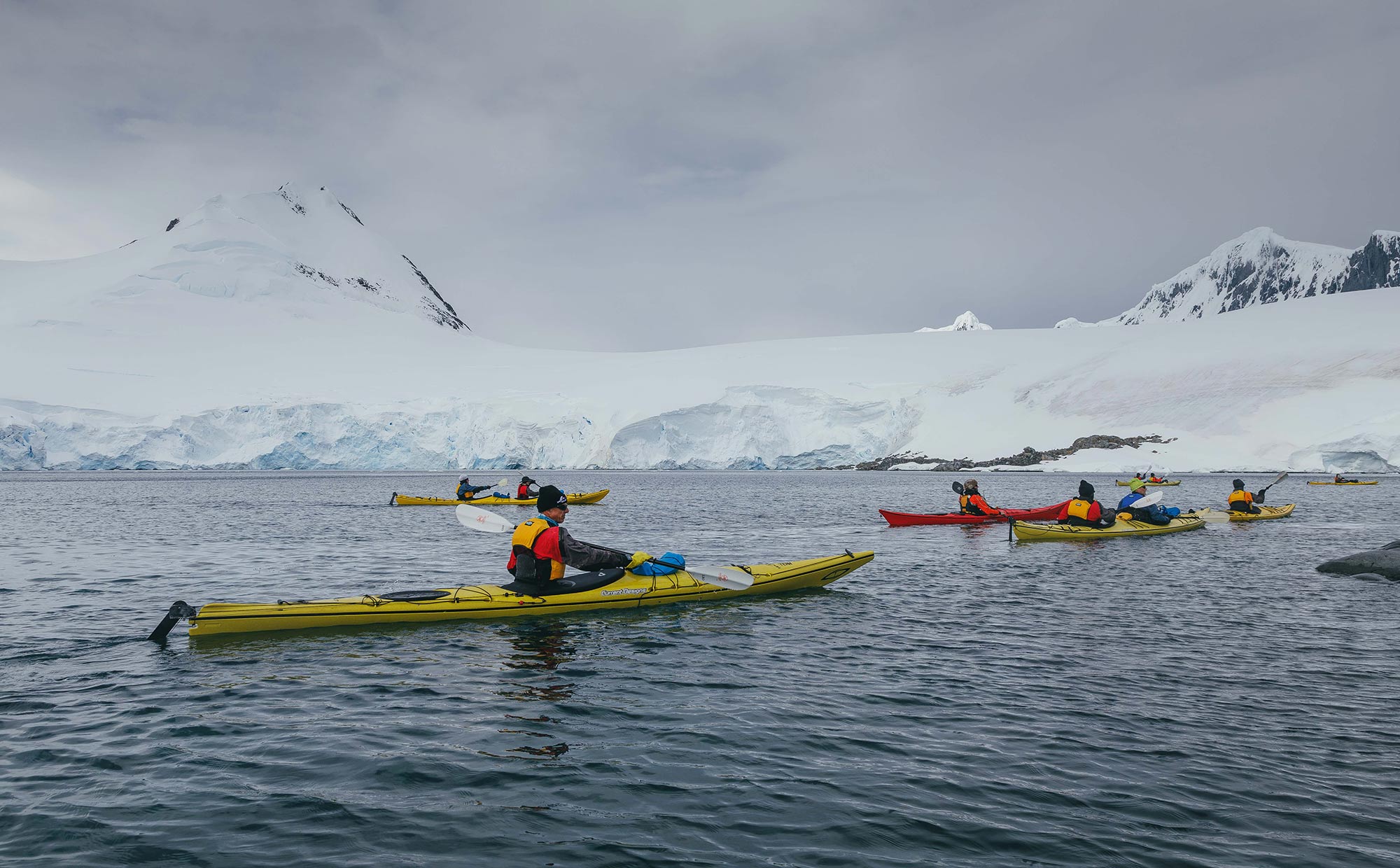 Passengers kayaking in Antarctic landscape