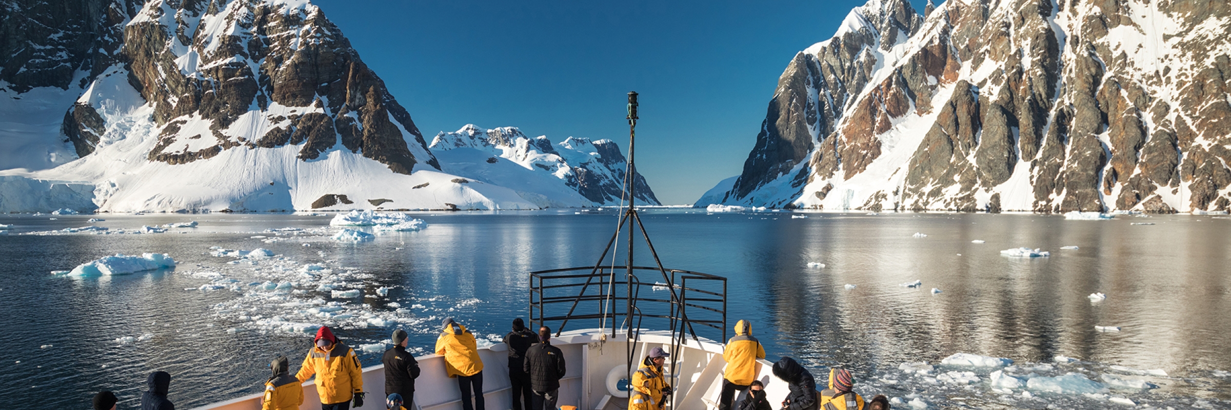 Passengers stand at the bow of the ship, as they cruise the Lemaire Channel. Photo: Acacia Johnson Photo by Acacia Johnson
