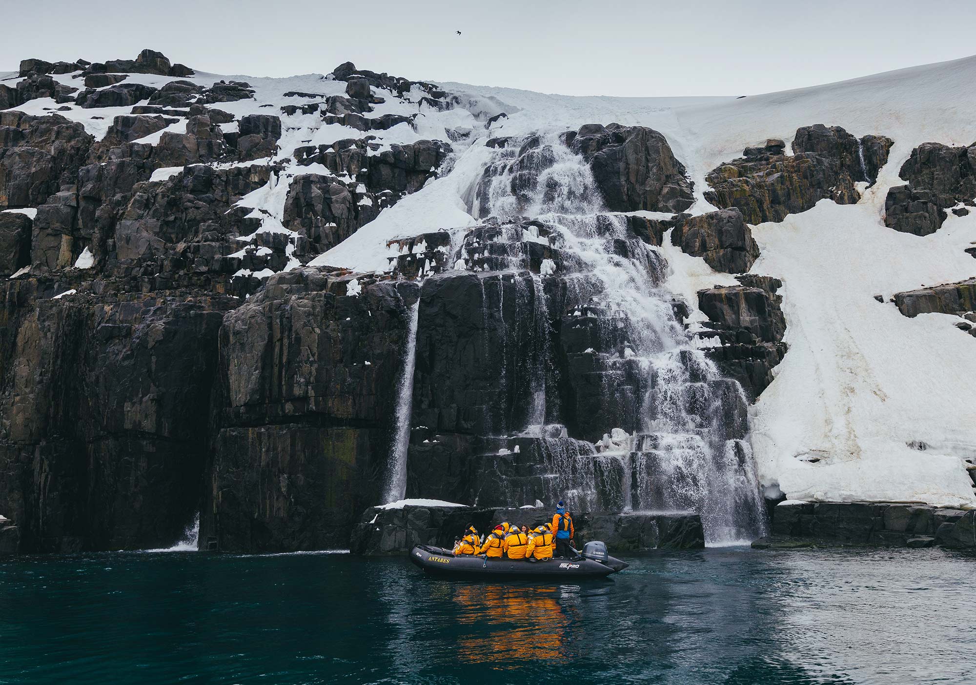 Zodiac cruising near waterfall in the Arctic