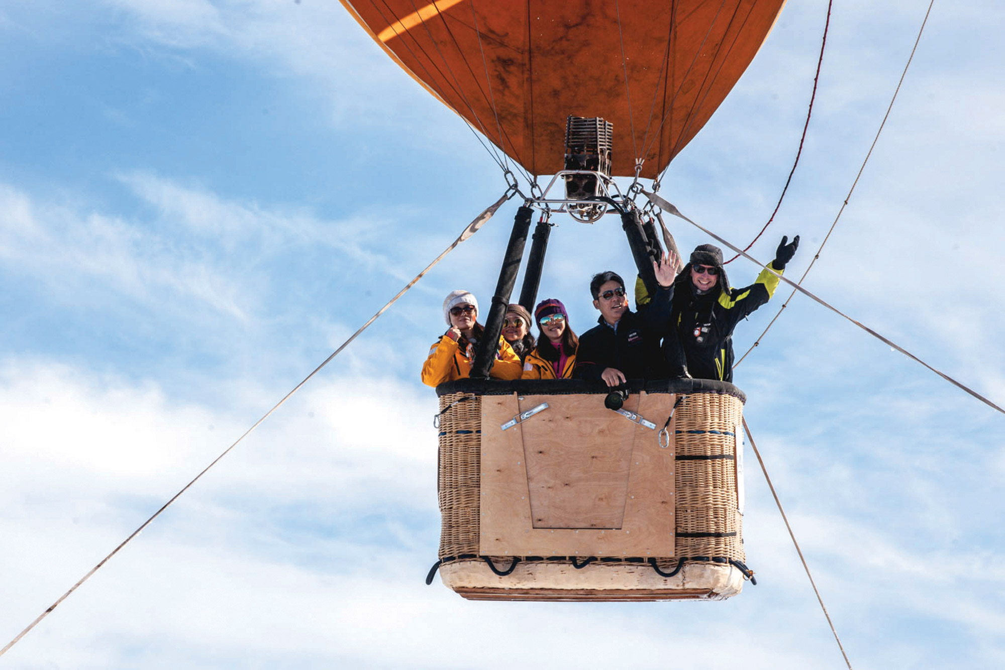 Passengers waving from hot air balloon